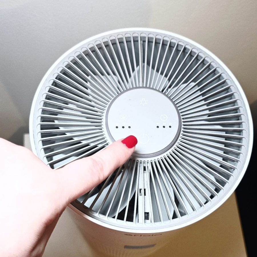 Top view of the purifier with my finger on the power button, showing fan speed and timer lights