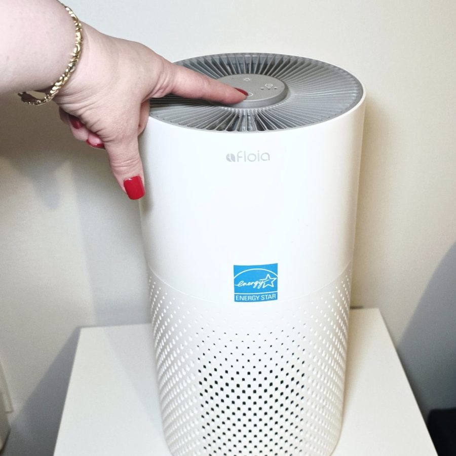 My hand pressing the power button on top of the Afloia air purifier
