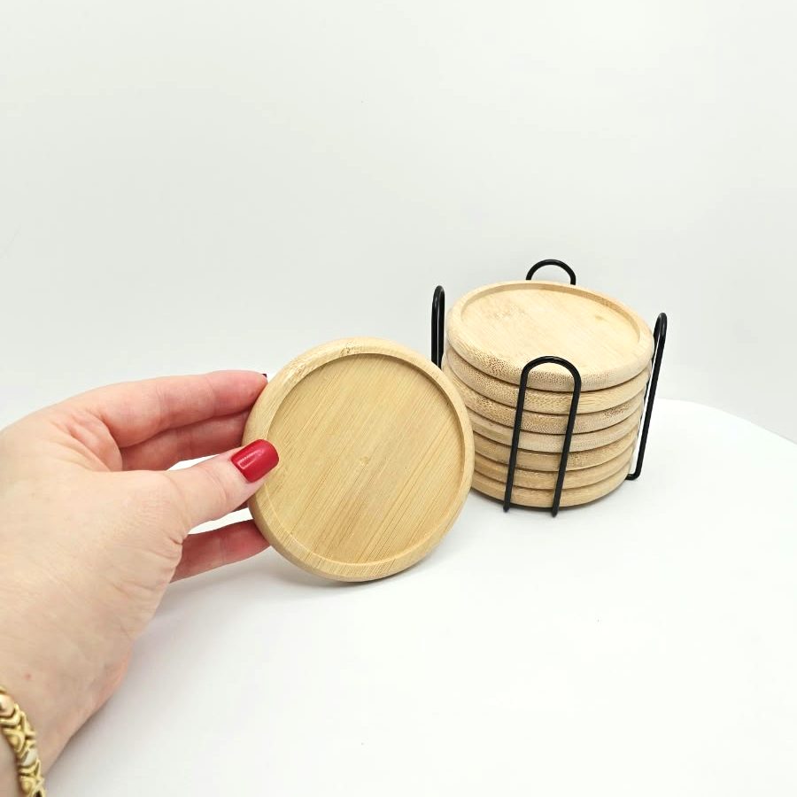 My hand holding one bamboo coaster next to the stack in its holder