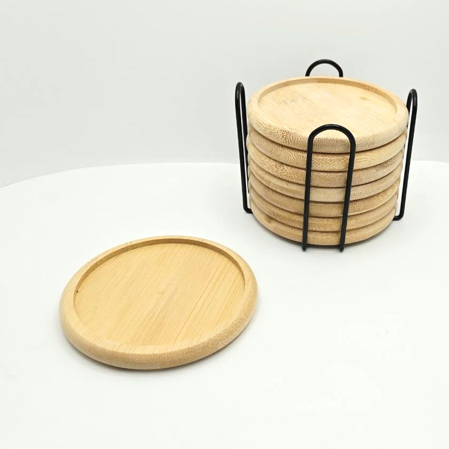 One bamboo coaster on the table next to the holder full of coasters