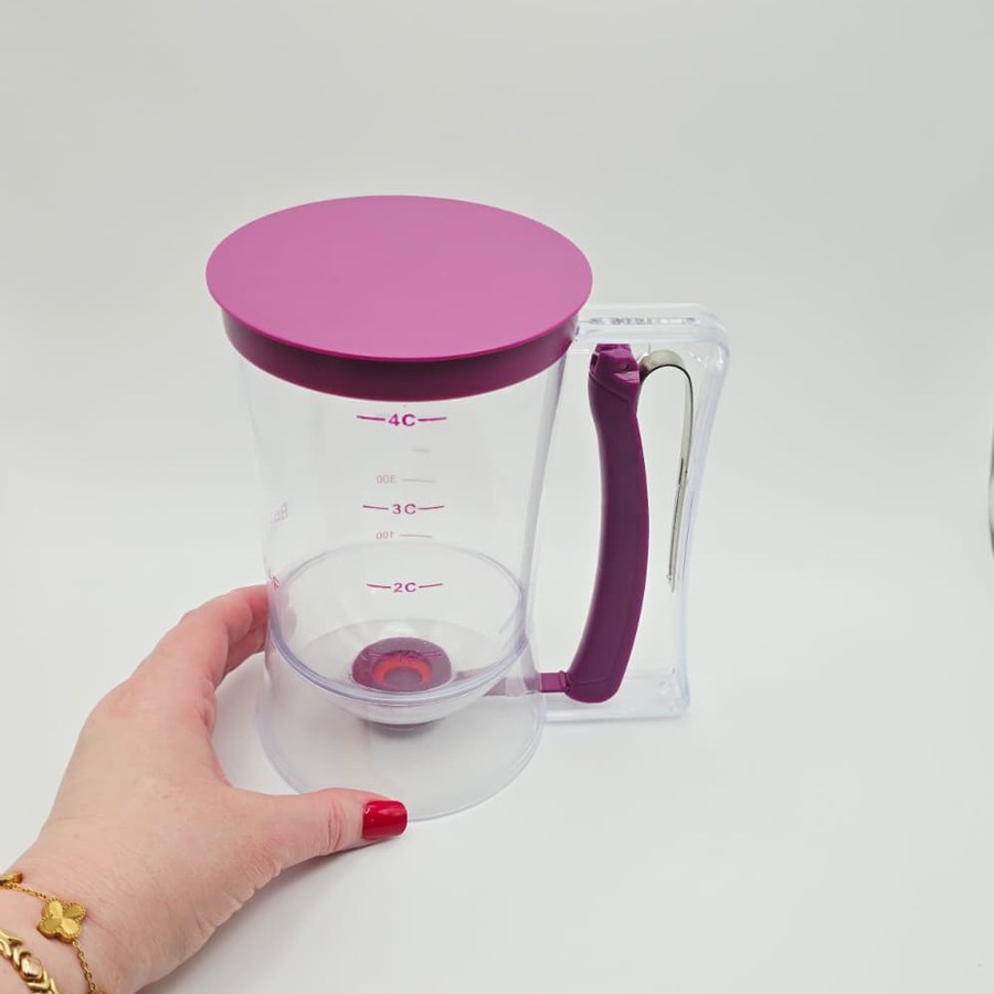 My hand next to my purple batter dispenser with the lid on and the 4-cup marks on the side