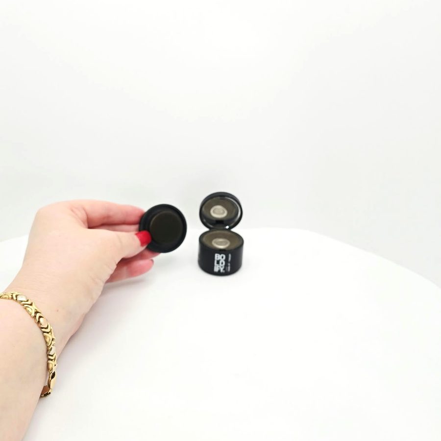 My hand holding the Boldify puff next to the open powder