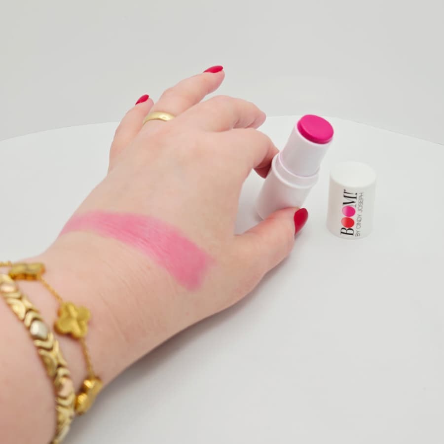 A swatch of my Peony Pink Boomstick on the back of my hand, next to the open stick and its cap