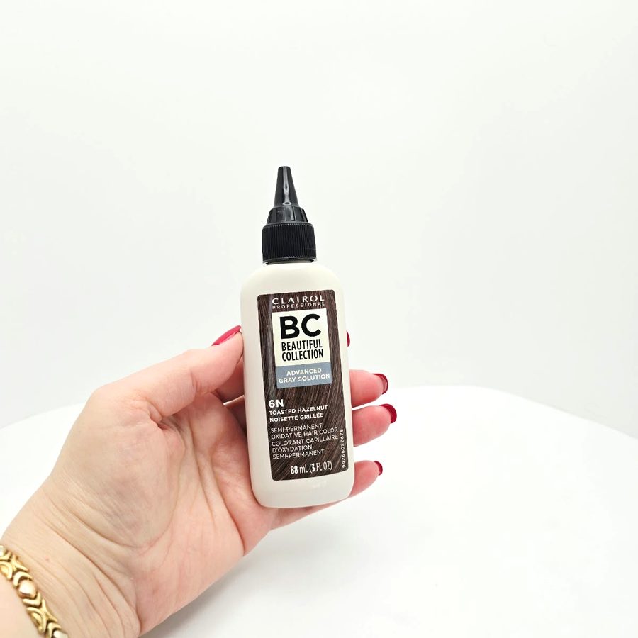My hand holding the Clairol 6N bottle, with the applicator tip on top