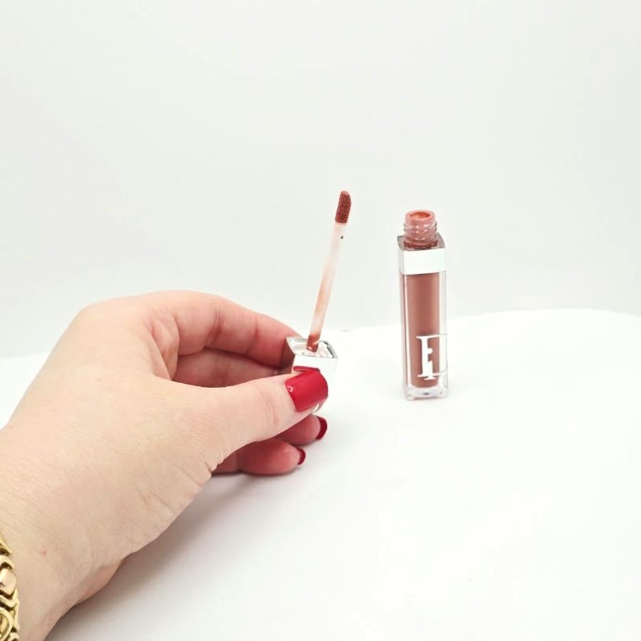 My hand holding the Dior gloss applicator next to the open tube