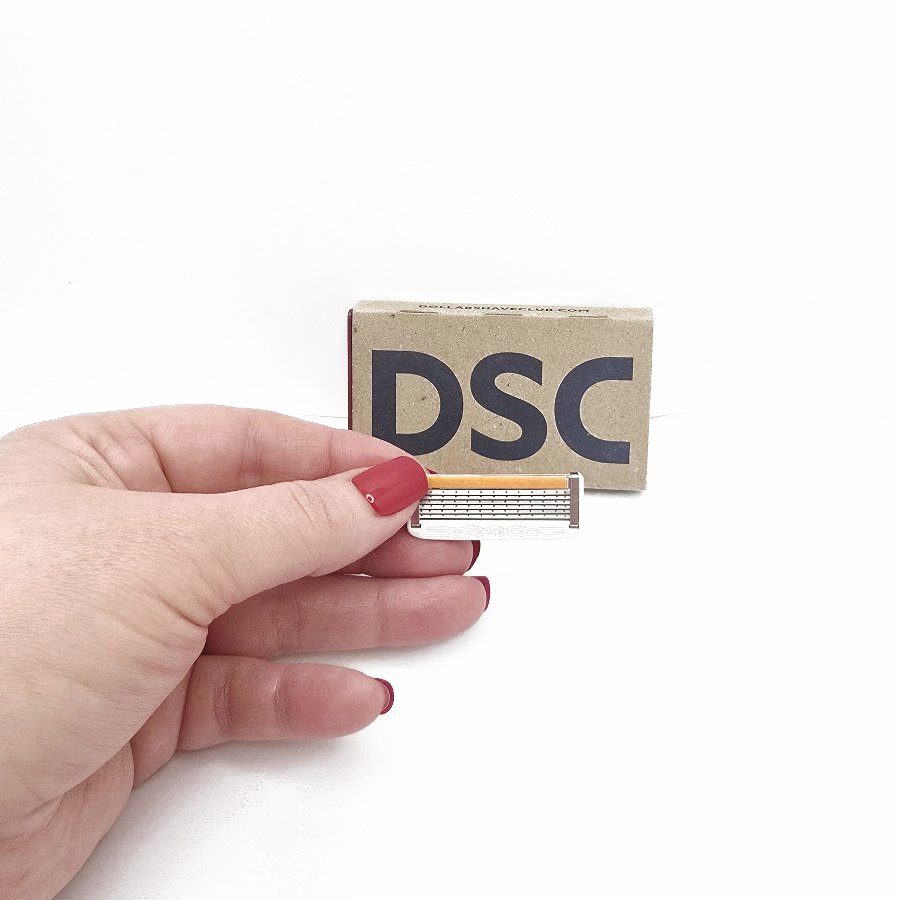 My hand holding a Dollar Shave Club 6 blade cartridge in front of the box