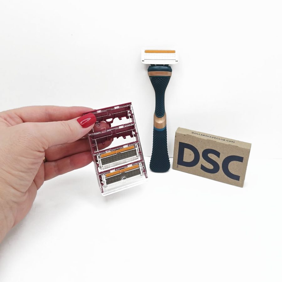 My hand holding the cartridge holder with spare blades next to the complete razor and the DSC box