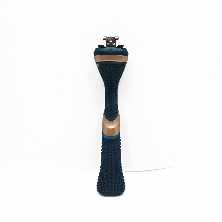 My blue and copper Dollar Shave Club razor handle standing on a white table