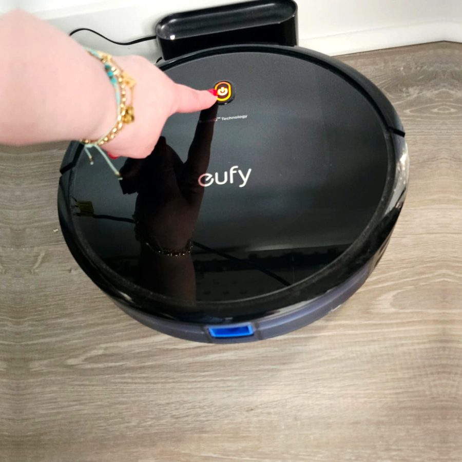 My finger pressing the power button on top of my eufy robot vacuum