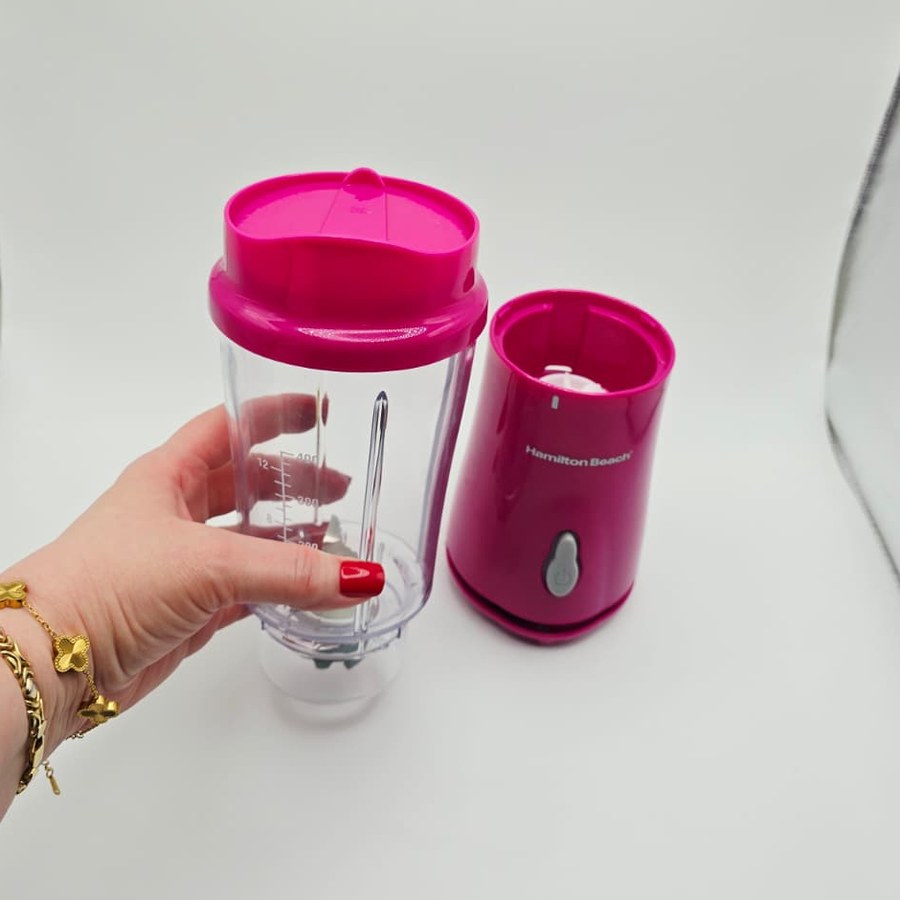 My hand holding the clear 14 oz blender jar beside the raspberry base