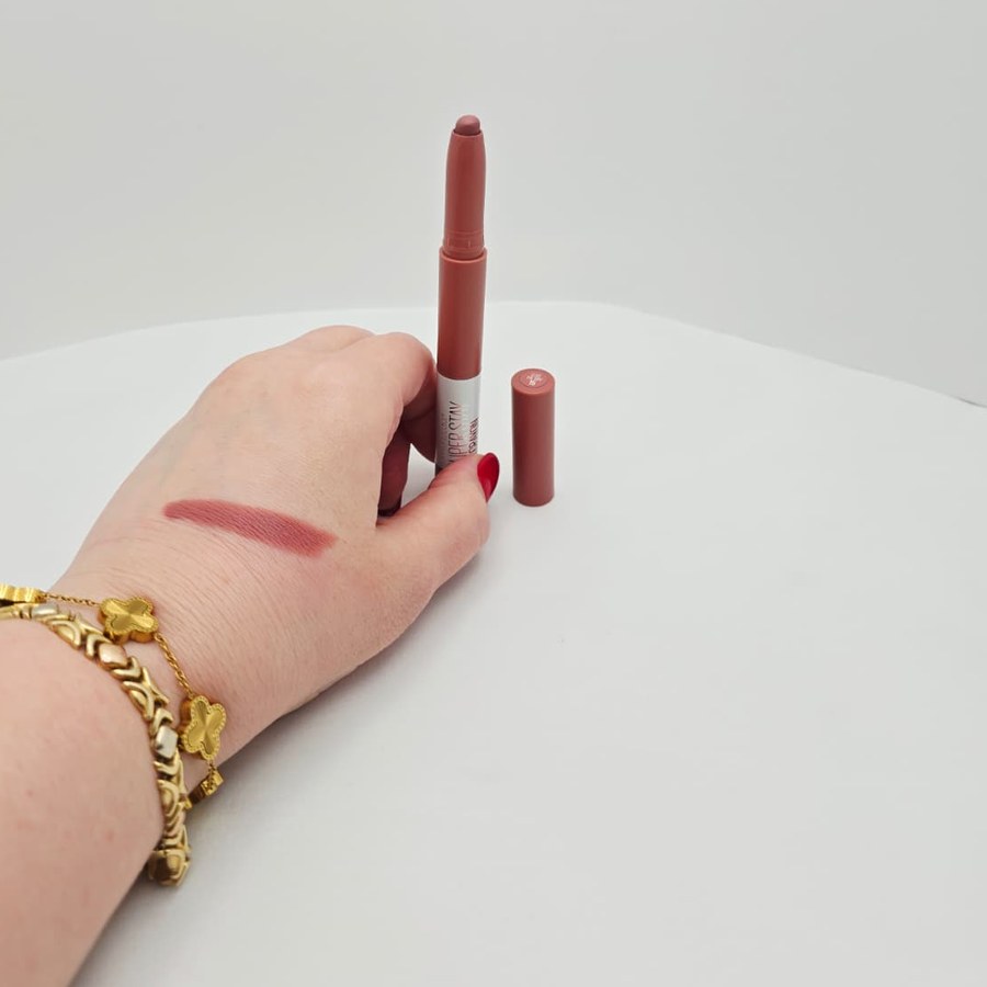My open Maybelline Super Stay Ink Crayon next to its cap, with a swatch on my hand