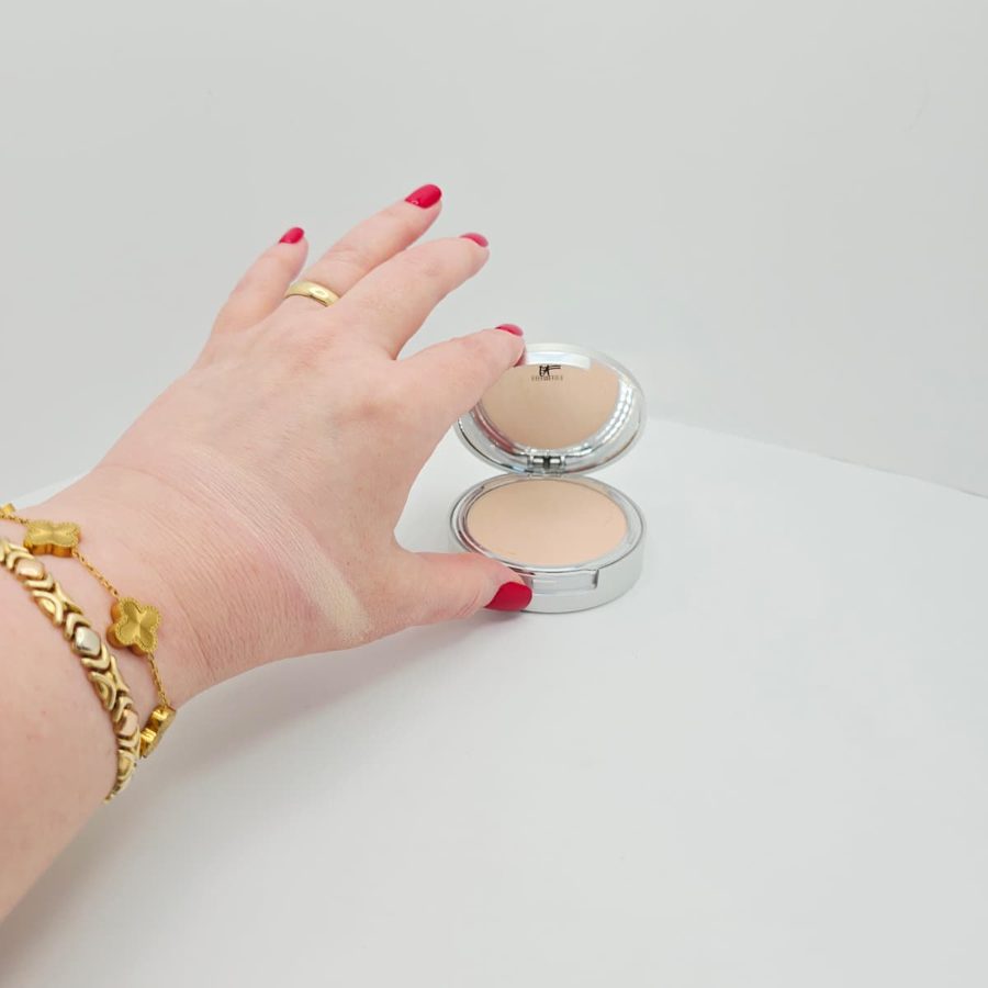 A swatch of my IT Cosmetics CC+ powder on the back of my hand, next to the open compact