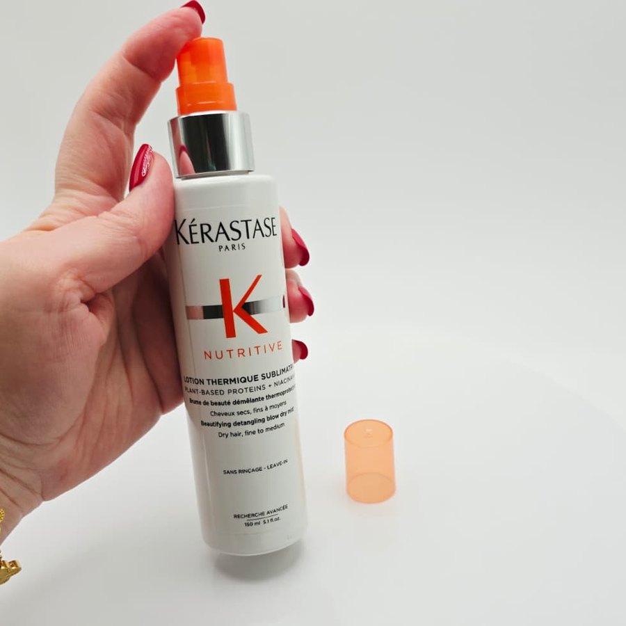 Holding my Kérastase Nutritive Lotion Thermique Sublimatrice, with its orange cap beside it