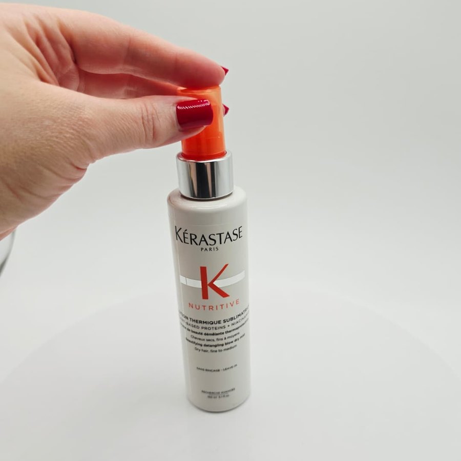 My finger on the orange pump of my Kérastase Nutritive blow-dry mist