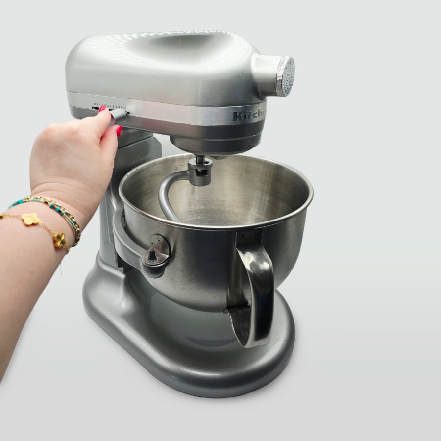 My hand on the speed lever of my silver KitchenAid bowl-lift mixer, with the dough hook attached