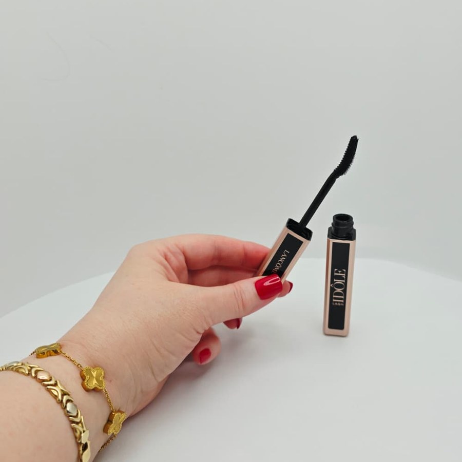 My hand holding the curved wand of my Lancôme Lash Idôle mascara next to the open tube