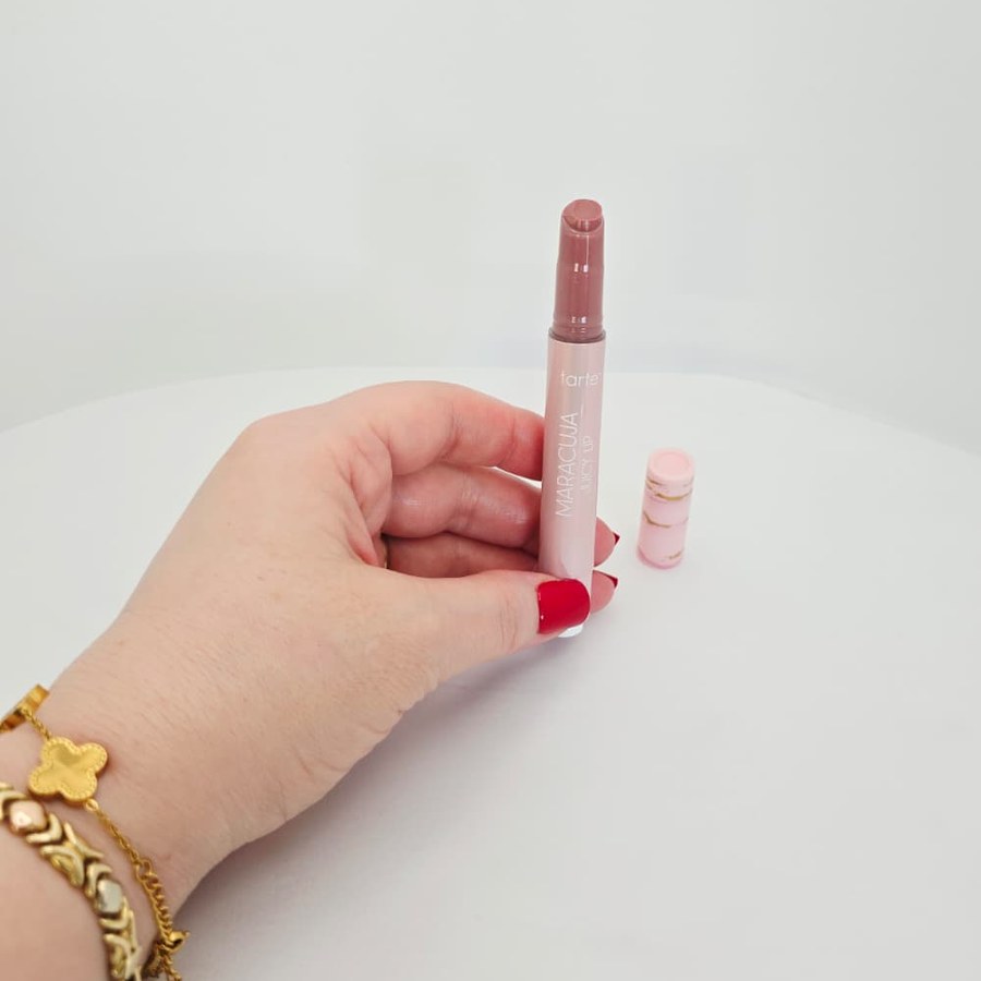 Holding my open tarte Maracuja Juicy Lip, with the cap beside it