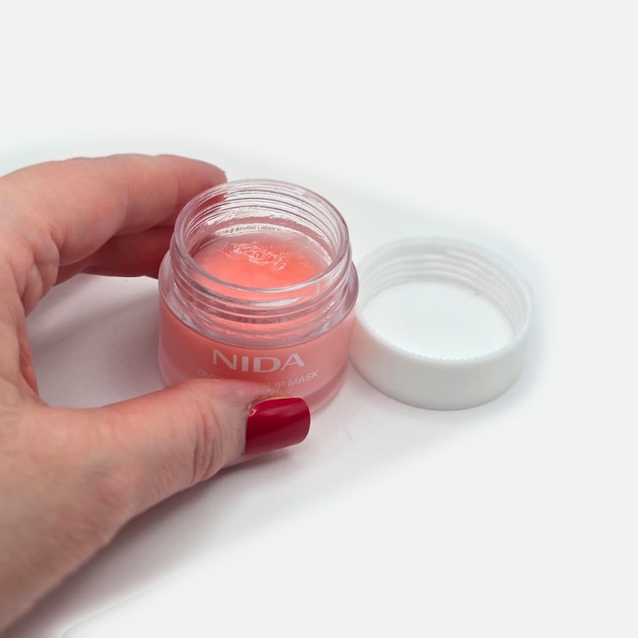 The NIDA lip mask jar open, showing the pink texture, with the white lid beside it