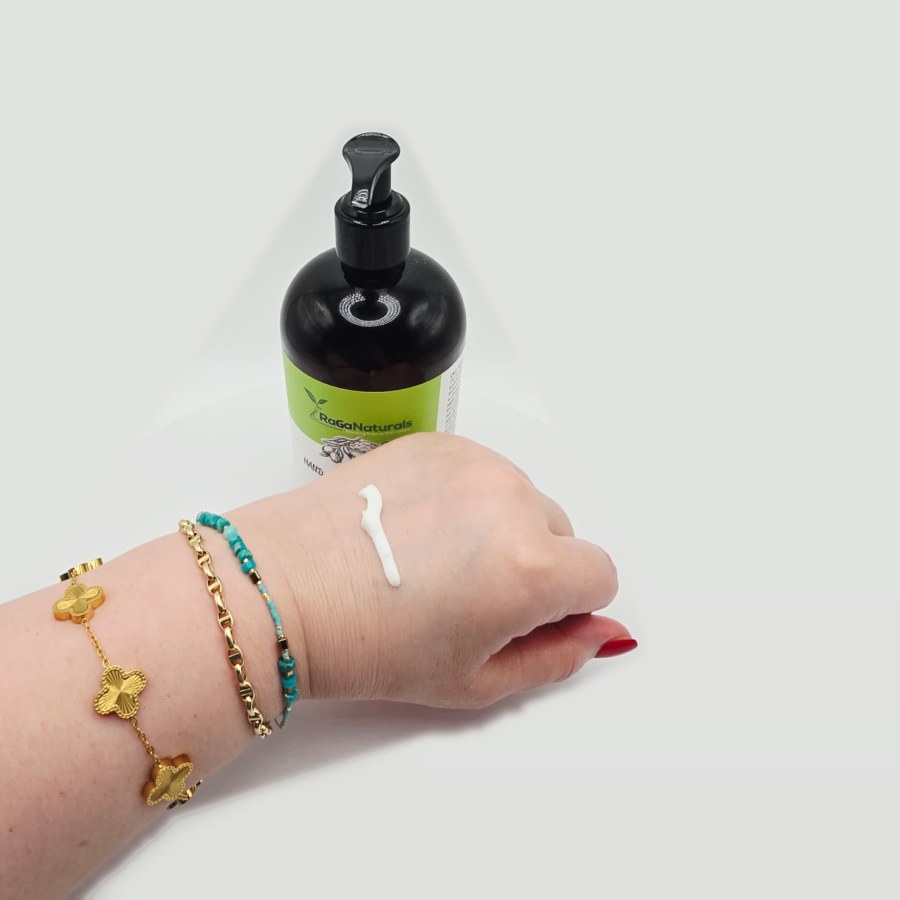 A line of RaGaNaturals shea butter lotion on the back of my hand, with the bottle behind