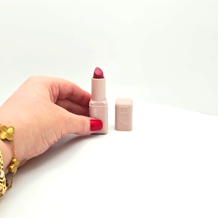 My hand holding the open Maybelline Serum Lipstick in Fit Check next to its cap