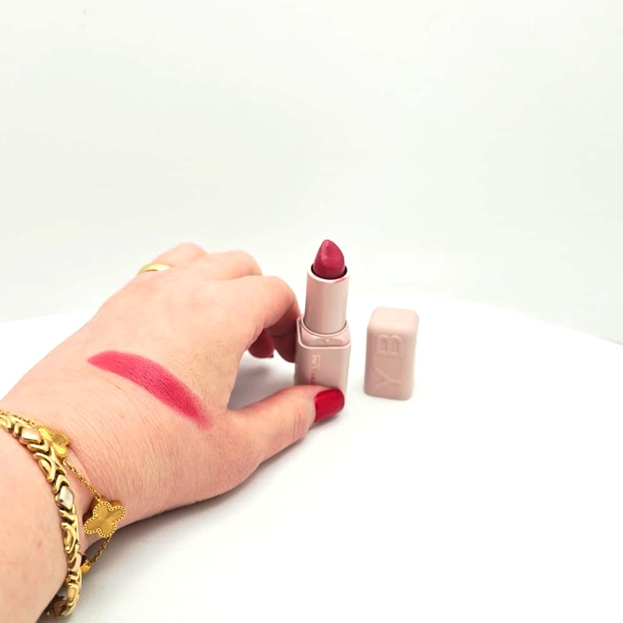 A swatch of Fit Check on the back of my hand, next to the open lipstick