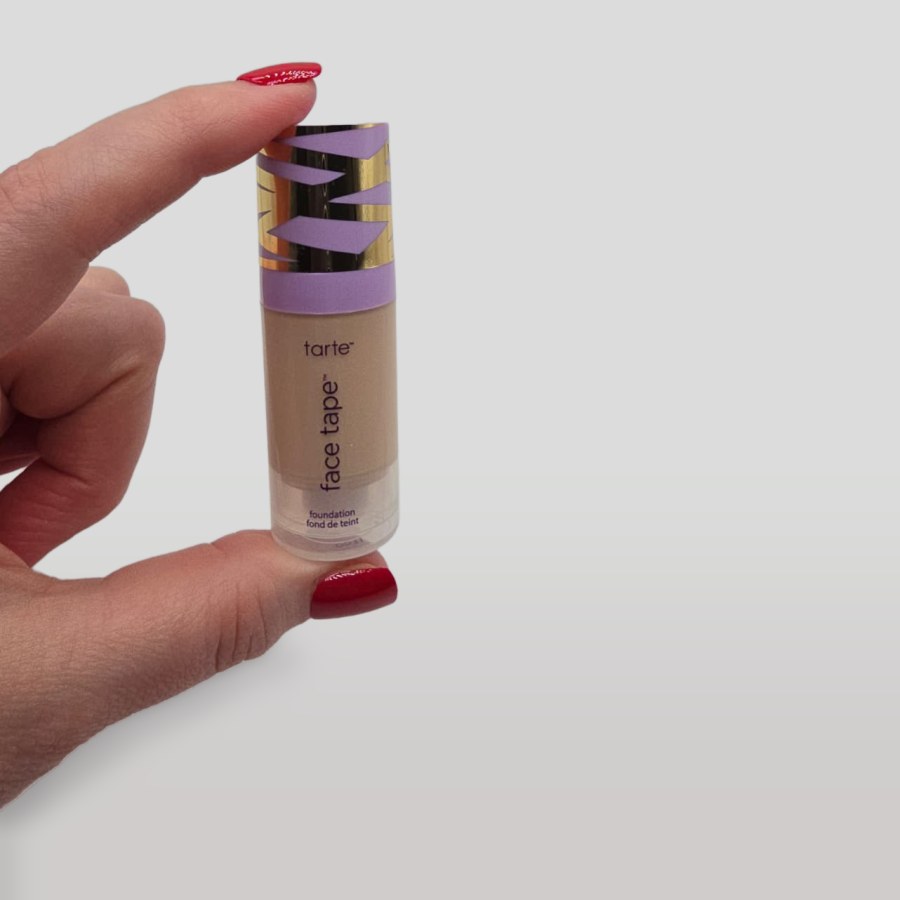 Holding my travel-size bottle of tarte face tape foundation