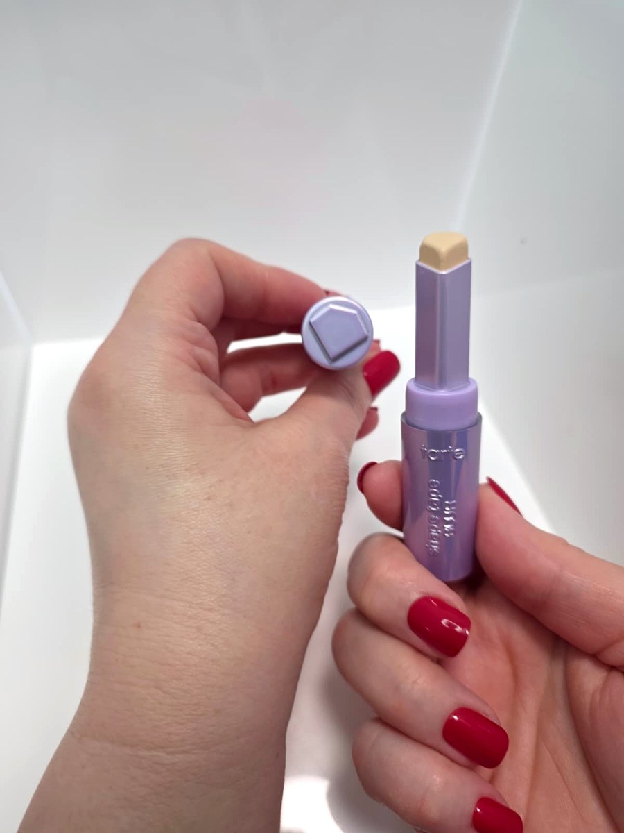 Holding the lavender Tarte Shape Tape Blur stick and its cap