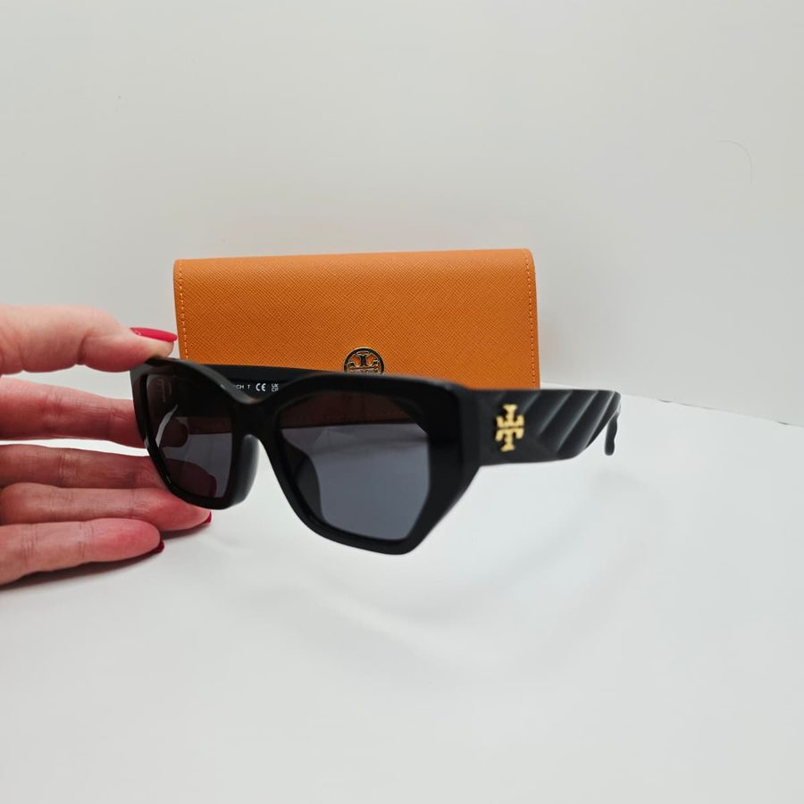 My hand holding my Tory Burch Kira sunglasses in front of the orange case