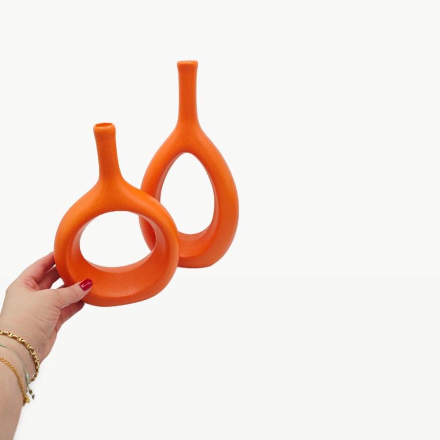 My hand next to my two orange XMGZQ hollow ceramic vases, the small round one in front and the tall one behind